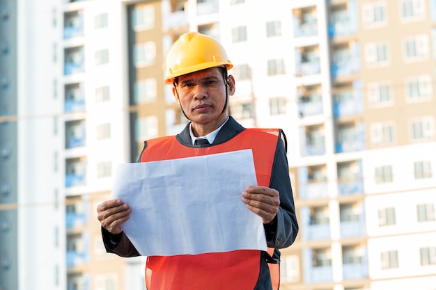 Ingeniero de pie para inspeccionar los planes de construcción en el sitio de construcción