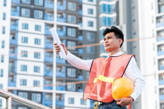 Ingeniero de pie para inspeccionar los planes de construcción en el sitio de construcción