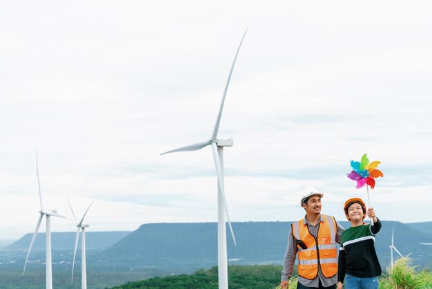 Ingeniero progresista con su hijo sosteniendo juguete de molino de viento en la montaña