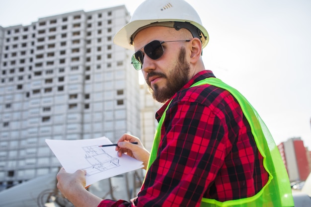 Ingeniero que controla los planos del sitio de construcción