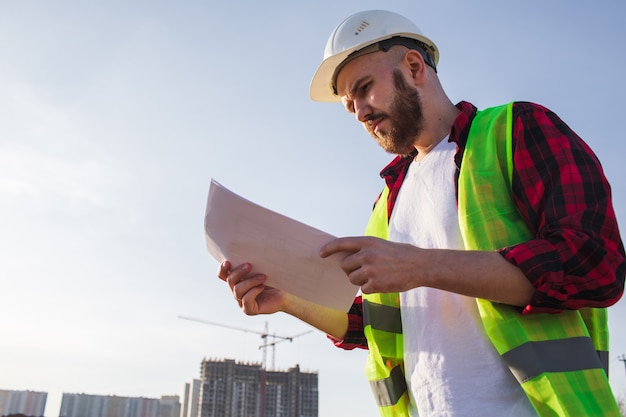 Ingeniero que controla los planos del sitio de construcción