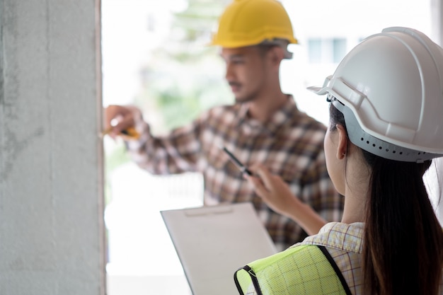 Foto ingeniero que verifica el defecto en el sitio de construcción midiendo la dimensión correcta de la columna de concreto