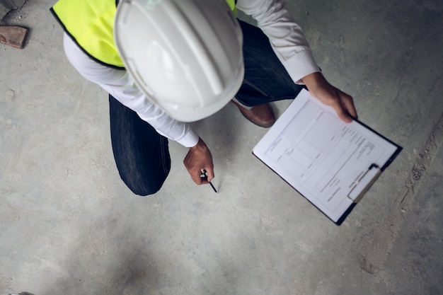 Foto ingeniero que verifica el defecto en el sitio de construcción sobre la superficie del piso de concreto