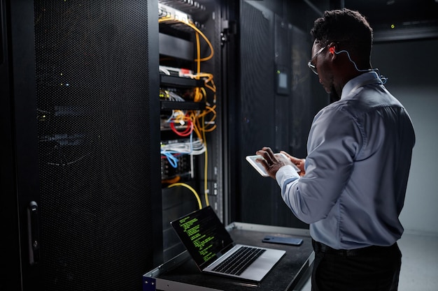 Ingeniero de red que usa una computadora portátil mientras configura servidores en el centro de datos