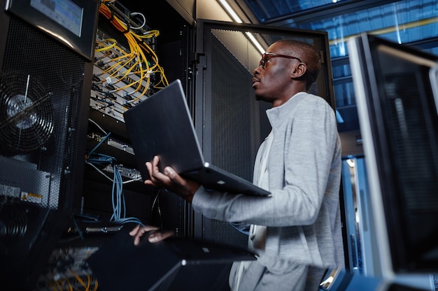 Ingeniero de redes que usa una computadora portátil en la sala de servidores