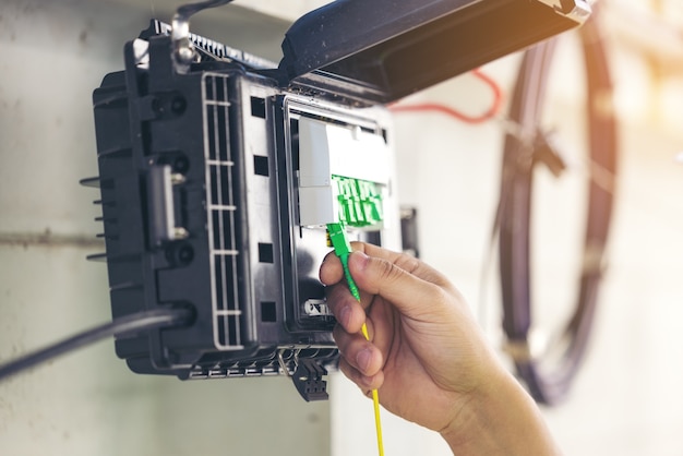 Foto ingeniero reparar el conector de las fibras en la bandeja del divisor de cerca fuera