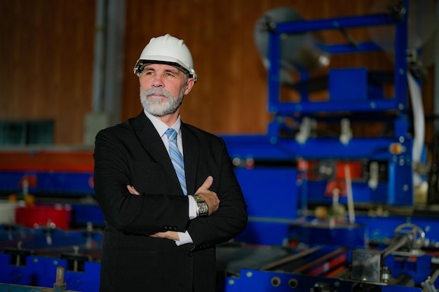 Ingeniero de retratos Jefe senior confiado en la fábrica de la industria Concepto de operación y mantenimiento de la industria inteligente Ingeniero mayor con bigote de barba en la cara de pie