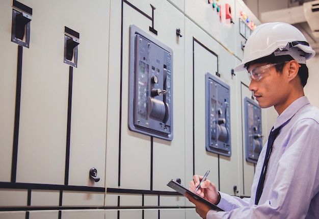 El ingeniero revisa el voltaje o la corriente por voltímetro en el panel de control de la planta de energía.