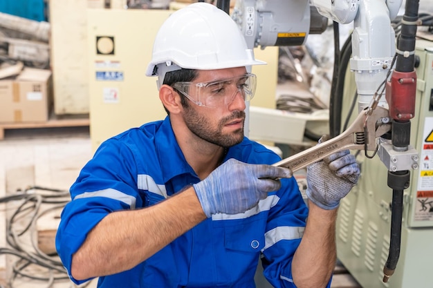 Ingeniero de robótica que trabaja en el mantenimiento de un brazo robótico moderno en el almacén de la fábrica