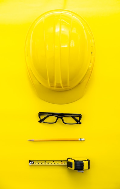 Foto ingeniero de seguridad amarillo y cartucho, lápiz, gafas poner sobre fondo amarillo