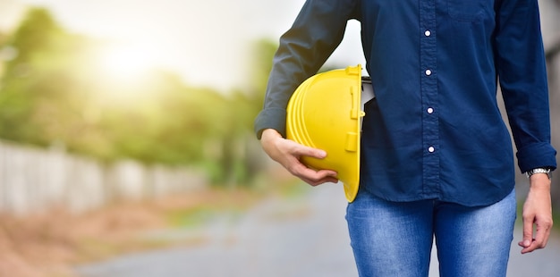 Ingeniero de sexo femenino que sostiene el casco al aire libre en el fondo de la construcción del sitio