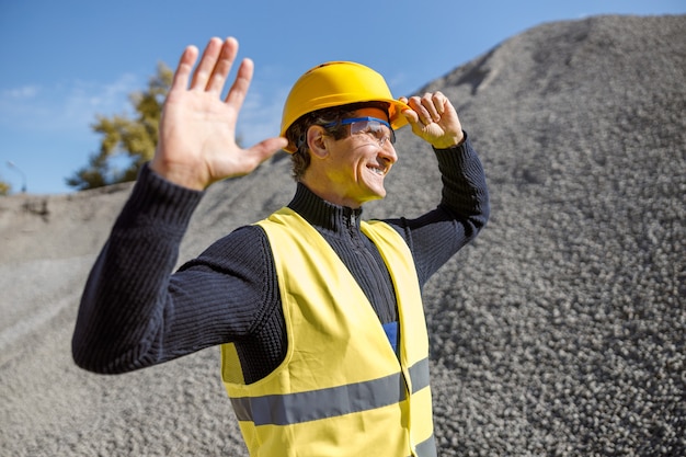 Ingeniero de sexo masculino alegre de pie al aire libre en la fábrica de cemento
