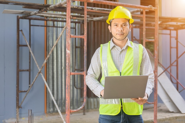 Un ingeniero de sexo masculino mira el plano del piso en el sitio de construcción.