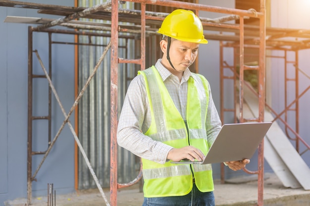 Un ingeniero de sexo masculino mira el plano del piso en el sitio de construcción.