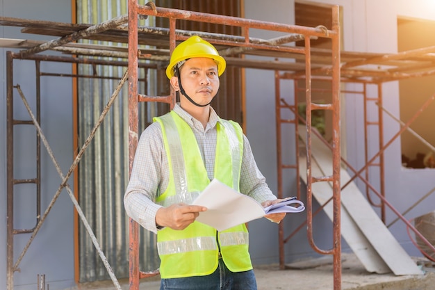 Un ingeniero de sexo masculino mira el plano del piso en el sitio de construcción.