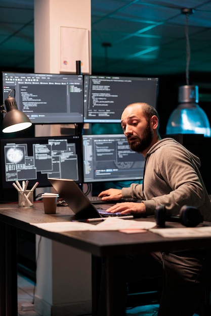 Ingeniero de software escribiendo código en varias pantallas que muestran algoritmos de inteligencia artificial a altas horas de la noche. Programación de computación en la nube en línea en monitores para desarrollar un nuevo script html.