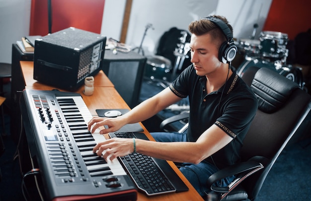 Ingeniero de sonido en auriculares trabajando y mezclando música en interiores en el estudio.