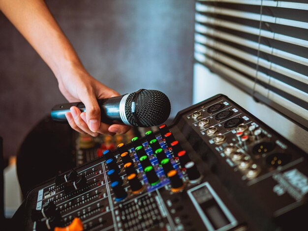 Foto ingeniero de sonido de mano sosteniendo el micrófono en el mezclador de sonido en la transmisión en vivo productor de estudio para el sonido