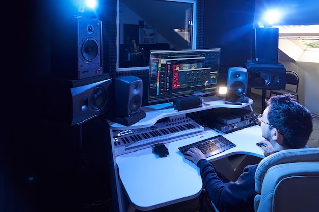 Ingeniero de sonido masculino profesional mezcla de audio en estudio de grabación. Tecnología de producción musical, trabajando en mezclador.