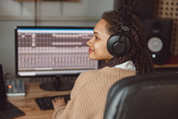 Foto el ingeniero de sonido se sienta en el escritorio con el panel de control del software de la estación de trabajo de audio digital graba una nueva pista