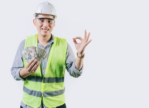 Ingeniero sonriente constructor sosteniendo dinero haciendo gestos ok aislado
