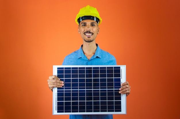 Foto ingeniero sosteniendo panel solar fotovoltaico hombre negro en casco de seguridad y camisa azul aislado