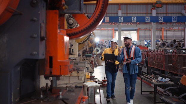 Ingeniero y técnico discutiendo maquinaria en la fábrica para planificar la inspección y el mantenimiento