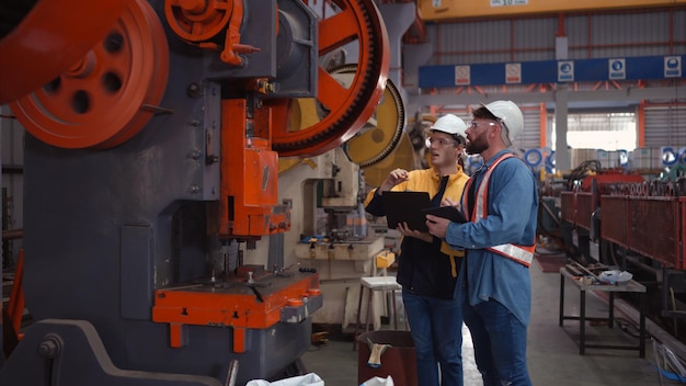 Ingeniero y técnico discutiendo maquinaria en la fábrica para planificar la inspección y el mantenimiento