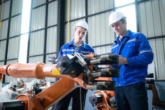 Ingeniero y técnico que trabaja con un brazo robótico en una fábrica Industria y concepto de ingeniería