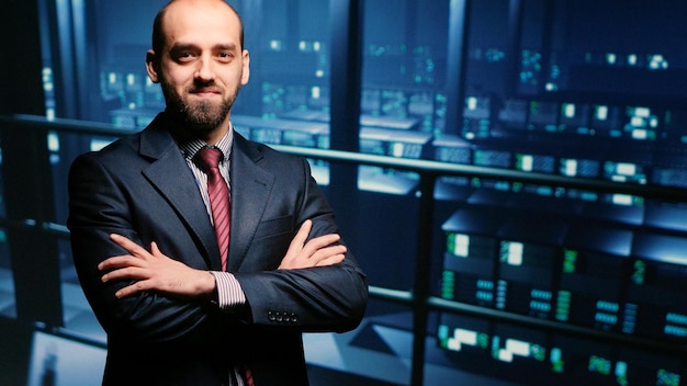 Ingeniero de TI parado junto a gabinetes de racks de servidores, revisando diagnósticos en el mainframe de la computadora. Administrador del sistema que ejecuta la verificación del sistema para la industria de la computación en la nube, seguridad cibernética.