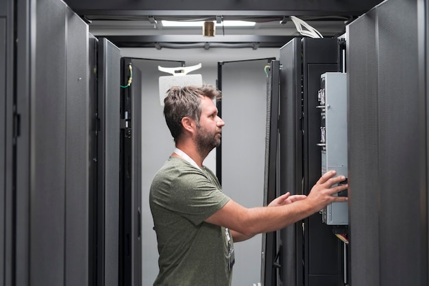 Ingeniero de TI que trabaja en la sala de servidores o en el centro de datos. El técnico coloca en un rack un nuevo servidor de una supercomputadora central de negocios corporativos o una granja minera de criptomonedas.