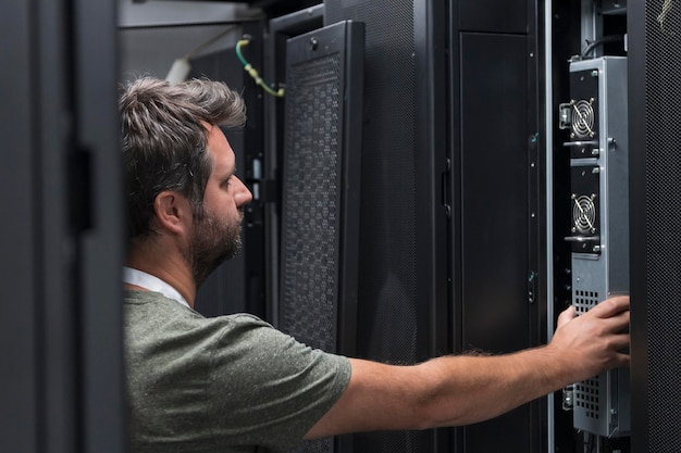 Ingeniero de TI que trabaja en la sala de servidores o en el centro de datos. El técnico coloca en un rack un nuevo servidor de una supercomputadora central de negocios corporativos o una granja minera de criptomonedas.