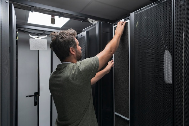 Ingeniero de TI que trabaja en la sala de servidores o en el centro de datos. El técnico coloca en un rack un nuevo servidor de una supercomputadora central de negocios corporativos o una granja minera de criptomonedas.