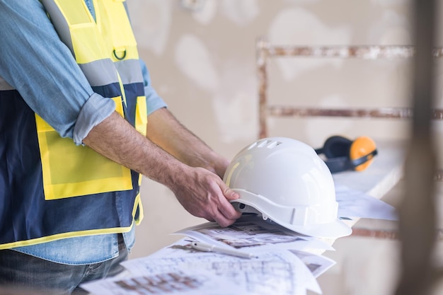 Ingeniero tomando un casco protector blanco antes de procesar una pared en mal estado en la premisa