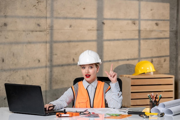 Foto ingeniero trabajador civil en casco y chaleco inteligente joven linda chica rubia que tiene una idea