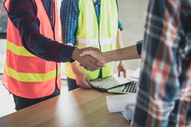 Ingeniero y trabajador dan la mano antes de planear y hablar de construcción