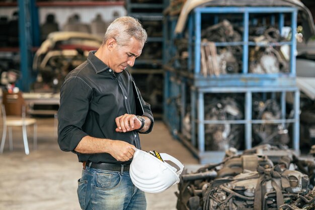 Ingeniero trabajador masculino que busca reloj de pulsera para preocuparse por el estrés con el concepto de tiempo de cita tardía de trabajo