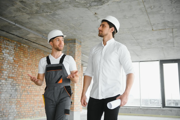 Ingeniero y trabajador revisando el proyecto en el sitio de construcción de fondo al atardecer en el tiempo de la tarde