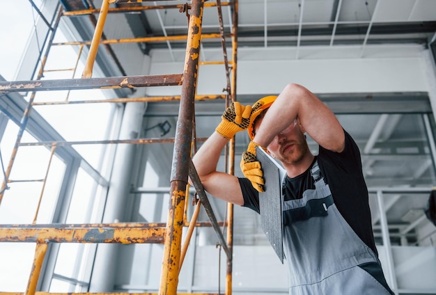 Ingeniero en uniforme gris toma un descanso en el interior de una gran oficina moderna durante el día