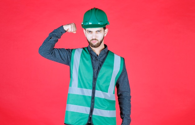 Ingeniero en uniforme verde y casco demostrando su puño.