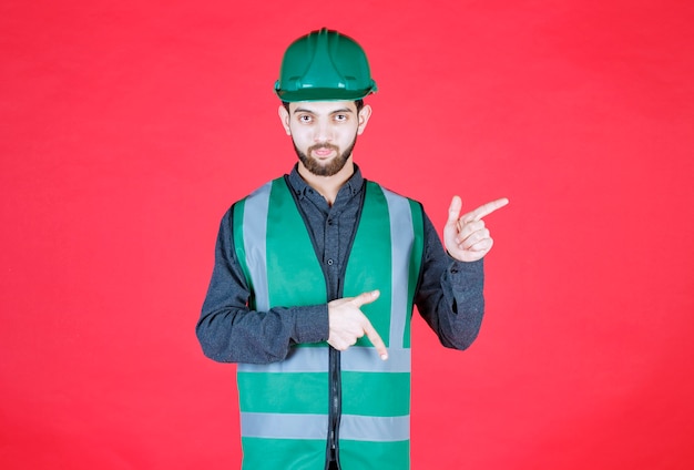 Ingeniero en uniforme verde y casco mostrando el lado derecho.