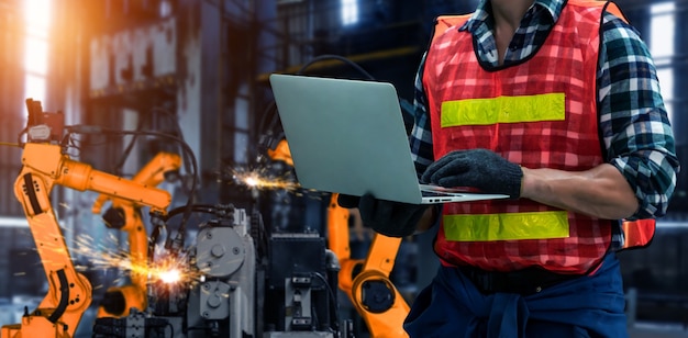 El ingeniero utiliza un software robótico avanzado para controlar el brazo robótico de la industria en la fábrica.