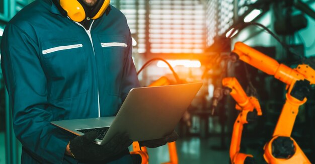 El ingeniero utiliza un software robótico avanzado para controlar el brazo robótico de la industria en la fábrica.