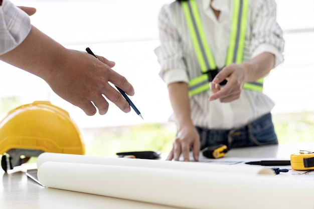 Ingenieros y arquitectos señalando los planos de la casa diseñados para el cliente, ambiente de encuentro, se reúnen para planificar la construcción y arreglarla. Ideas de diseño e interiorismo.