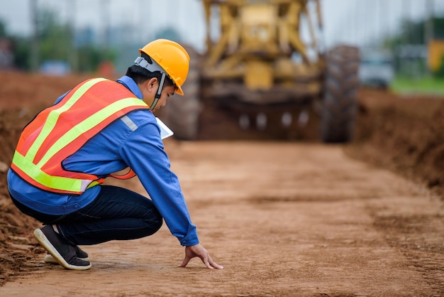 Los ingenieros asiáticos observan la reconstrucción de carreteras e inspeccionan la construcción de la carretera en el sitio de construcción.