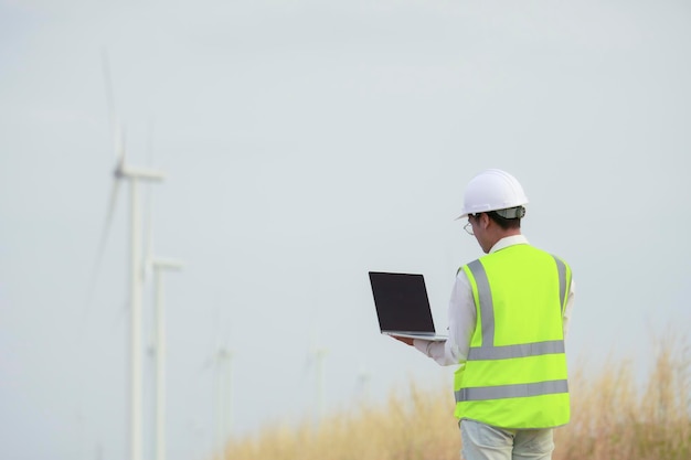 Ingenieros asiáticos revisando turbinas eólicas industria de energía ecológica campo de molinos de viento