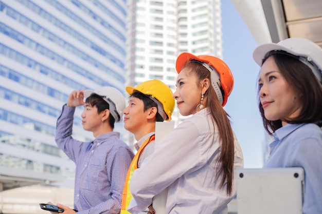 Ingenieros asiáticos sosteniendo un casco de seguridad blanco mirando hacia adelante