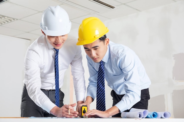 Foto ingenieros en cascos de pie junto a la fábrica.