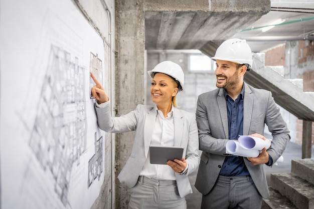 Ingenieros civiles trabajando juntos en el sitio de construcción controlando e inspeccionando el proceso de construcción