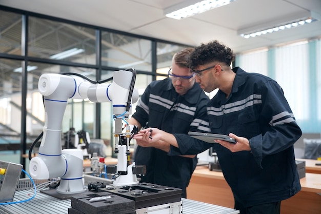 Los ingenieros de control de robótica resuelven problemas y configuran la programación del panel de control para el controlador de brazo de robot industrial en la planta de producción